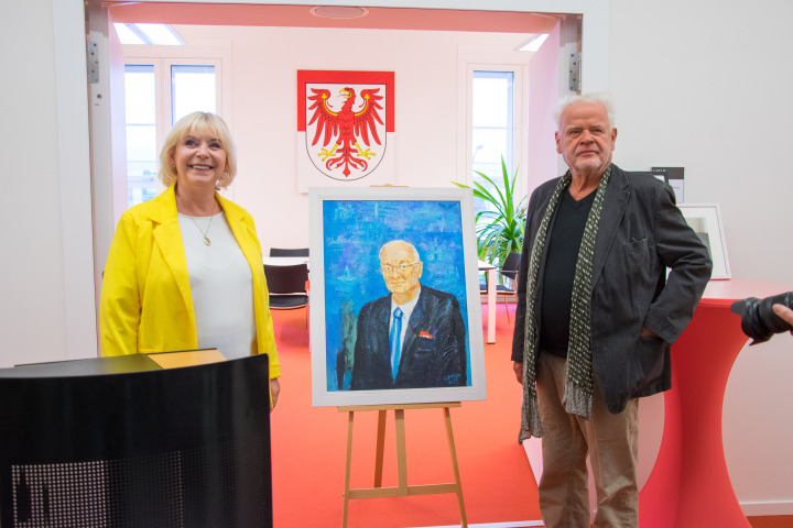 Landtagspräsidentin Prof. Dr. Ulrike Liedtke (l.) und der Künstler Christian Heinze (r.) präsentieren das Porträt des ehemaligen Landtagspräsidenten Dr. Herbert Knoblich.